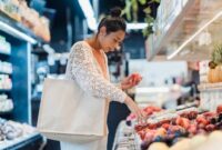 Seorang warga menggunakan tas belanja ramah lingkungan saat memilih produk lokal segar di pasar tradisional. Kebiasaan sederhana ini menjadi salah satu pilar penunjang strategi nasional dalam menekan emisi karbon dari sektor konsumsi harian.