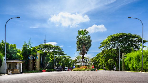Seorang pejalan kaki menggunakan payung untuk melindungi diri dari terik matahari yang menyengat di kawasan bisnis Jakarta, menggambarkan dampak perubahan suhu udara ekstrem di kawasan perkotaan.