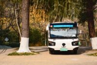 Suasana bus listrik perkotaan yang melintasi jalanan bersih di pagi hari, melambangkan transisi transportasi publik ramah lingkungan demi menekan emisi gas buang kendaraan.