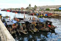 Suasana pagi hari di salah satu desa nelayan pesisir Indonesia saat para warga bergotong-royong menyiapkan perahu dan jaring sebelum melaut.