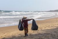 Pemandangan pesisir pantai Indonesia yang memperlihatkan kontras antara keindahan laut biru dan pentingnya menjaga ekosistem dari ancaman limbah plastik.