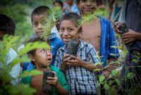 Aktivitas warga perkotaan saat menanam bibit pohon lokal dalam aksi pemulihan hutan komunitas sebagai bagian dari tren gaya hidup ramah lingkungan.