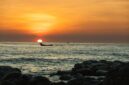 Seorang nelayan tradisional di pesisir kepulauan Indonesia bersiap melaut dengan perahu kerajinan tangan di bawah naungan cahaya matahari terbenam.