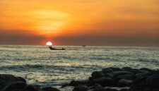 Seorang nelayan tradisional di pesisir kepulauan Indonesia bersiap melaut dengan perahu kerajinan tangan di bawah naungan cahaya matahari terbenam.