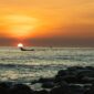 Seorang nelayan tradisional di pesisir kepulauan Indonesia bersiap melaut dengan perahu kerajinan tangan di bawah naungan cahaya matahari terbenam.