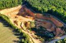 Pemandangan udara memperlihatkan bukit-bukit yang terkelupas akibat aktivitas pertambangan terbuka, memperlihatkan dampak langsung pengerukan tanah terhadap ekosistem hutan tropis Nusantara.