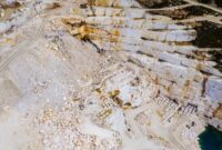 Pemandangan dari udara memperlihatkan kawasan pertambangan terbuka di wilayah pesisir Indonesia yang mengubah bentang alam hijau menjadi area industri pengolahan mineral mentah.