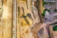 Pemandangan udara lokasi penambangan terbuka di Indonesia yang memperlihatkan alih fungsi lahan tropis dan perubahan warna perairan pesisir. Kerusakan ekosistem ini menjadi harga mahal di balik melonjaknya permintaan komoditas mineral untuk teknologi modern.